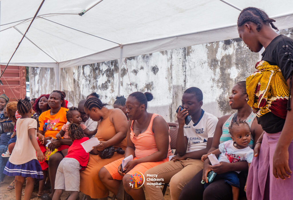 Families waiting under a tent at a free medical mission
