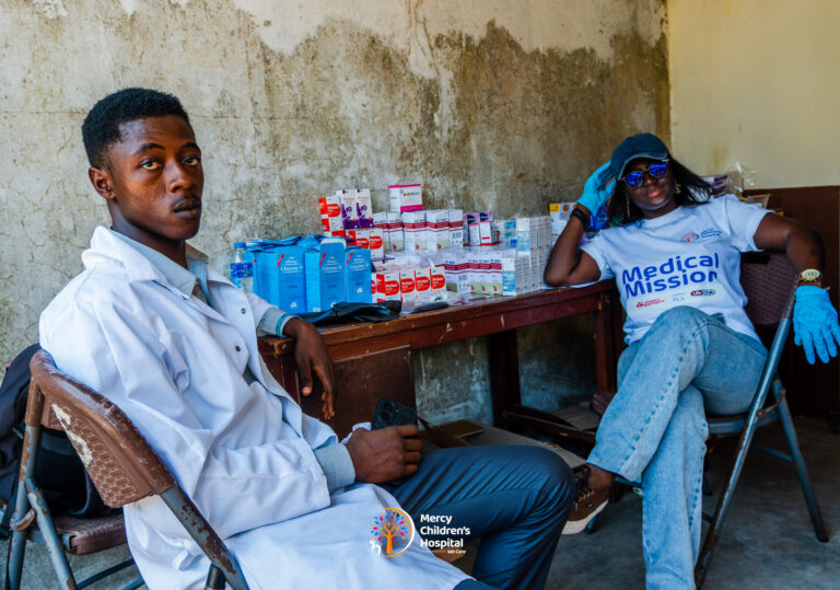 Pharmacy staff at a table stocked with medicines